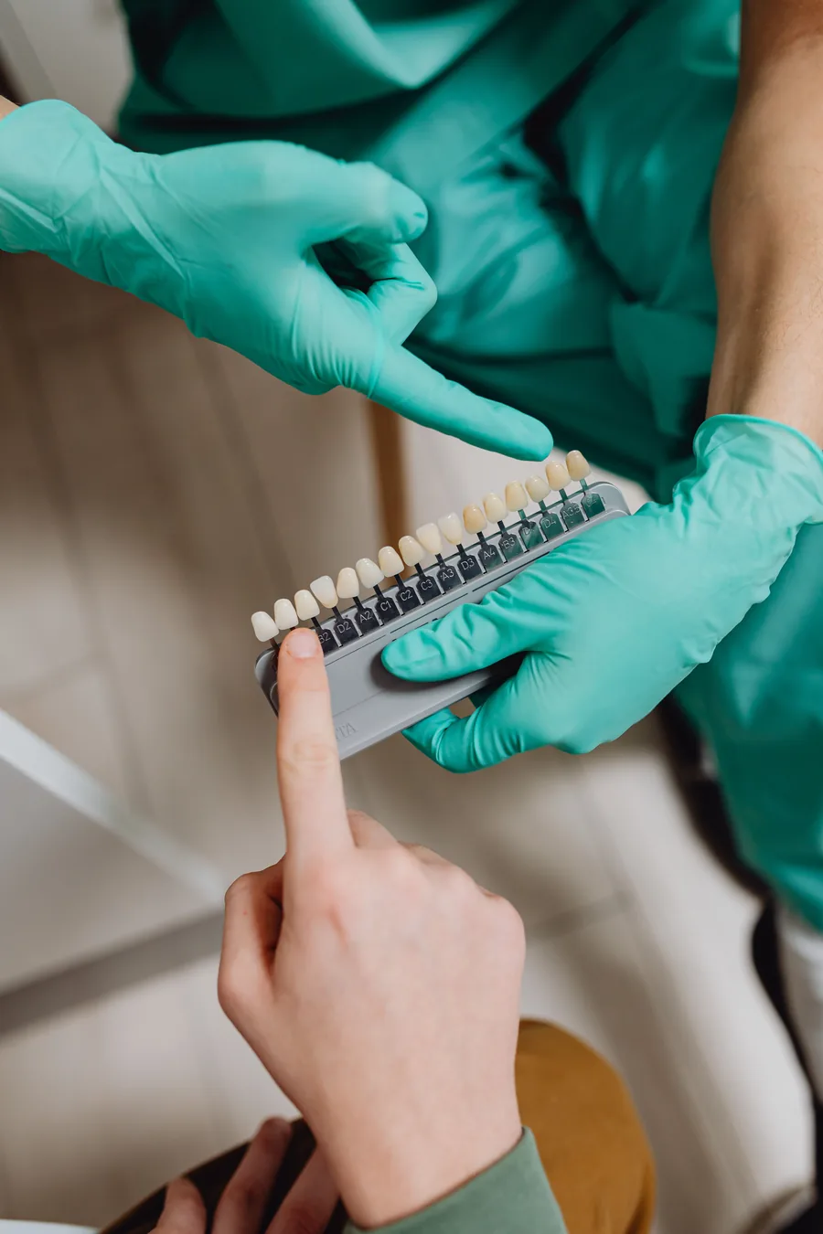 Dentist comparing a tooth shade guide with a patient for cosmetic treatment planning